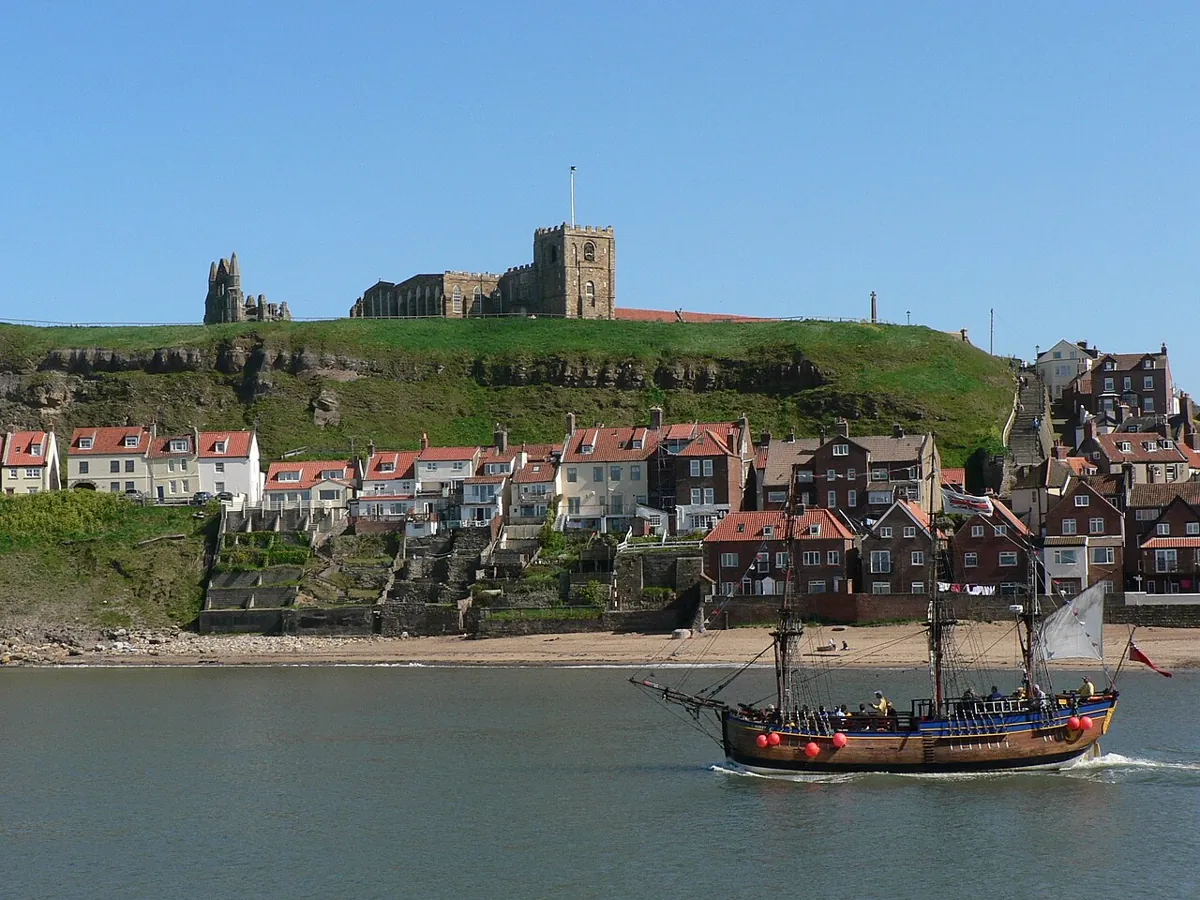 Sailing ship in Whitby harbour below St Mary's Church and Whitby Abbey.